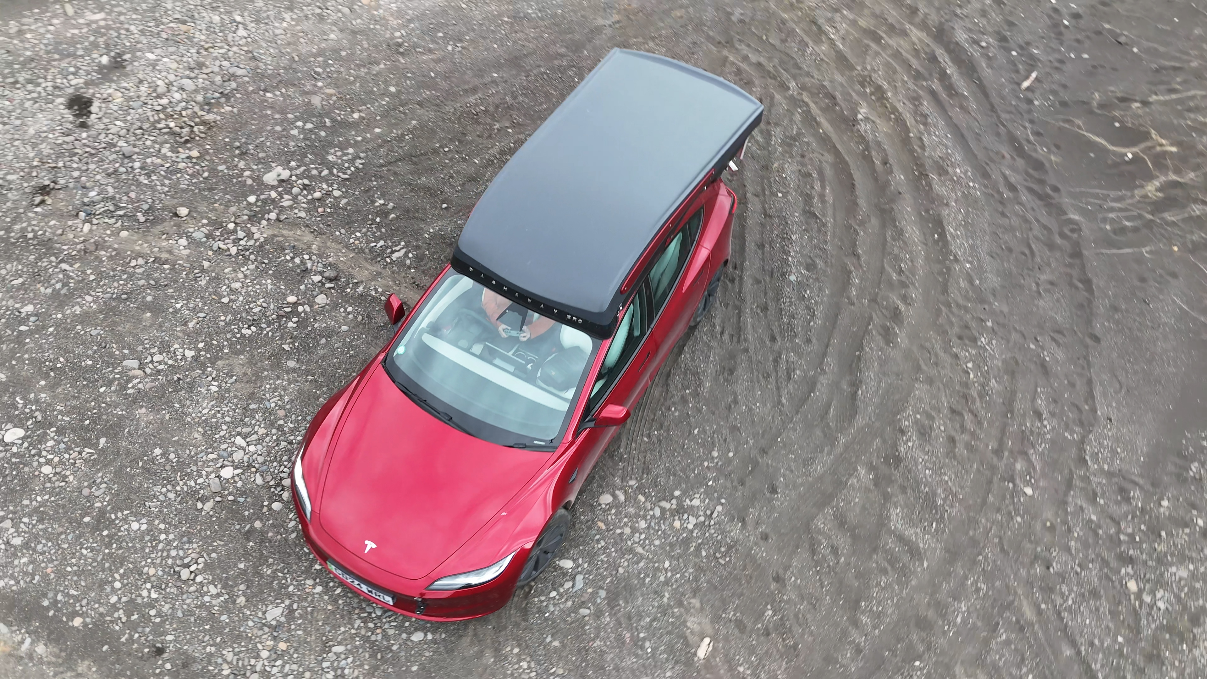 Drone overhead shot of Tesla with roof camper on volcanic ground, Iceland