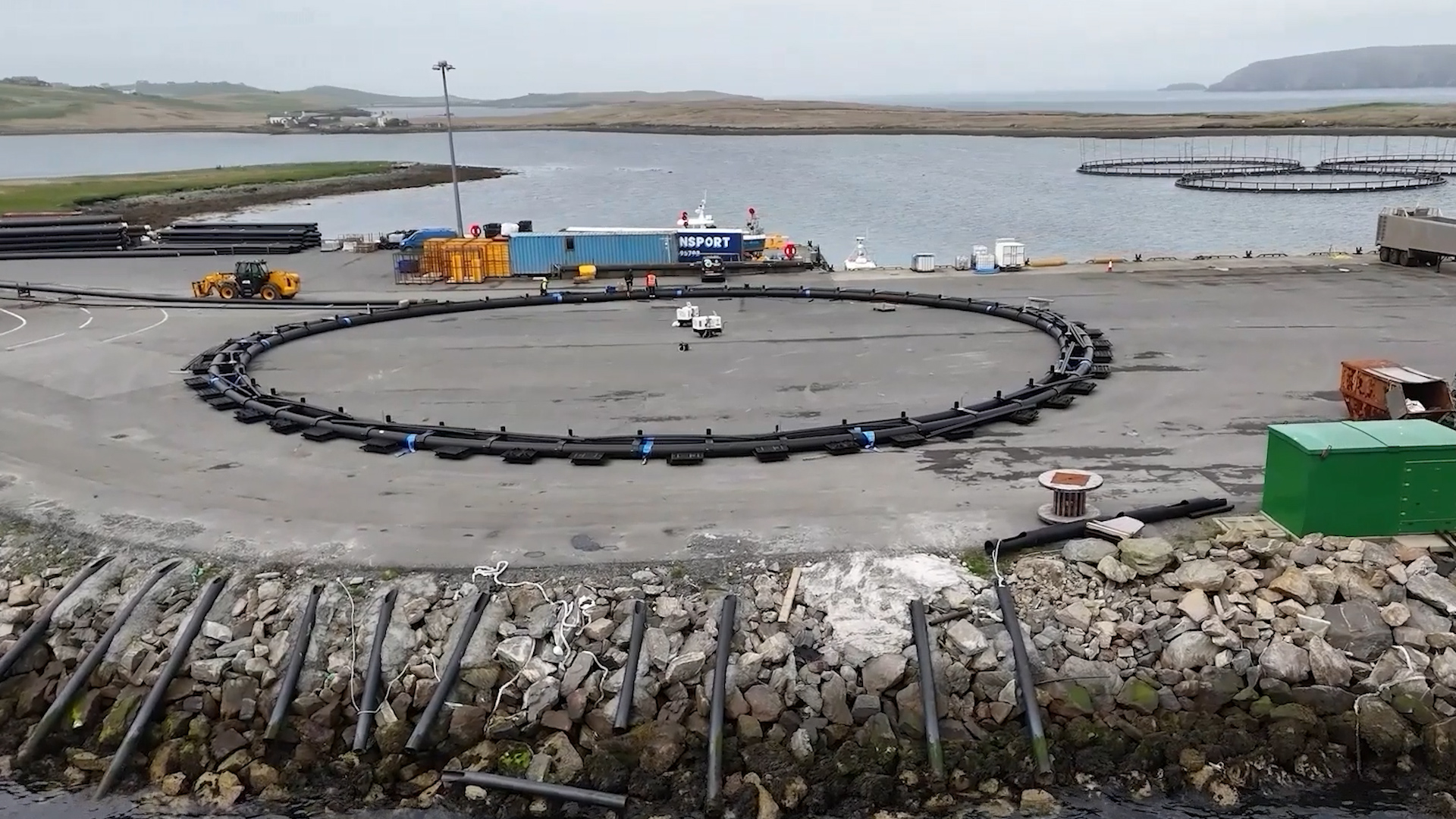 Aerial drone view of harbour infrastructure project with fish farm ring on Yell, Shetland